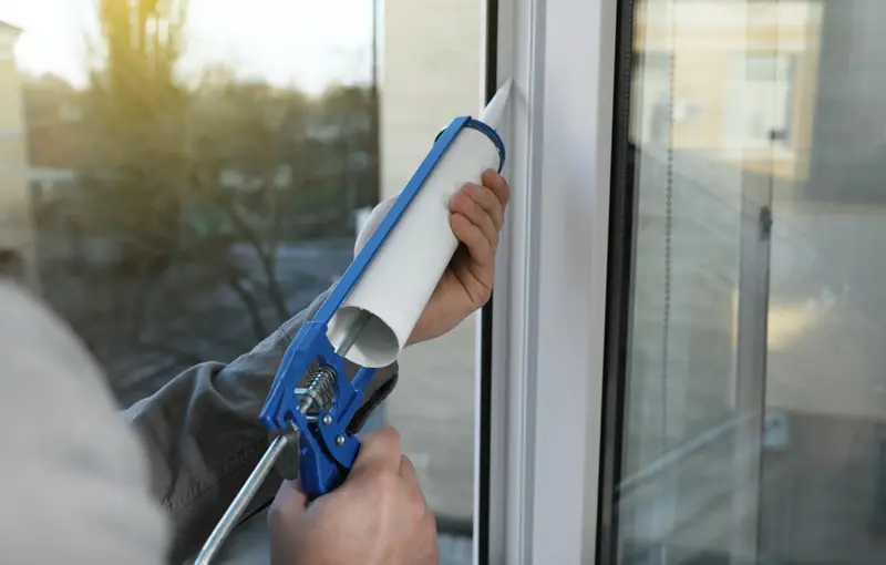 someone installing caulking around a window